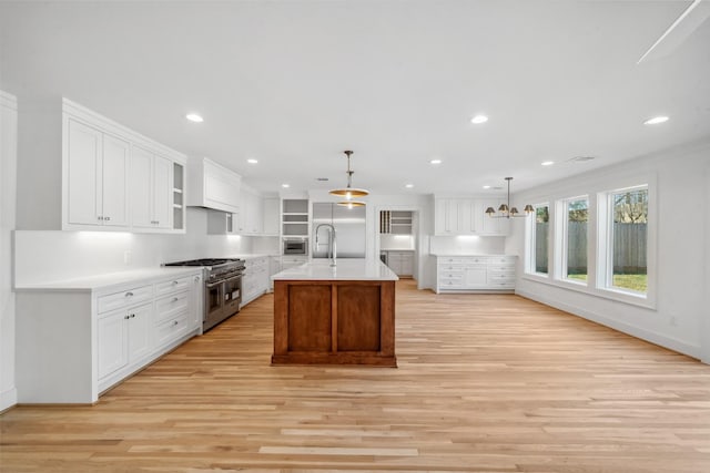 kitchen with high end appliances, light countertops, white cabinets, and a sink