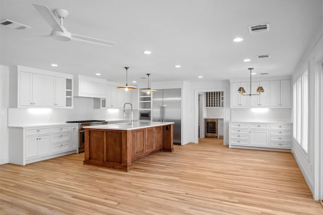 kitchen featuring premium appliances, light countertops, light wood finished floors, and open shelves