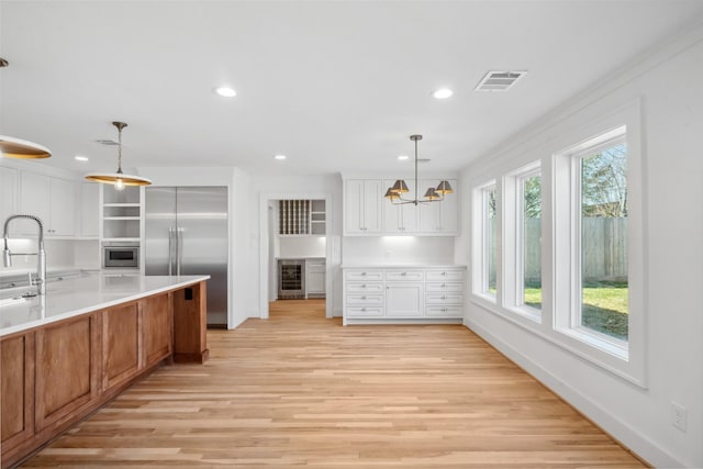 kitchen with beverage cooler, visible vents, light wood-style flooring, and built in refrigerator