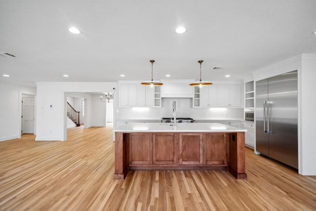 kitchen featuring built in fridge, light countertops, visible vents, and open shelves