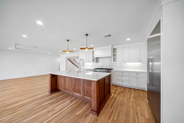 kitchen with light wood-style floors, white cabinets, a sink, and built in fridge