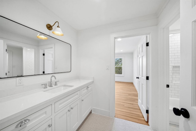 bathroom with wood finished floors, vanity, baseboards, and a bath