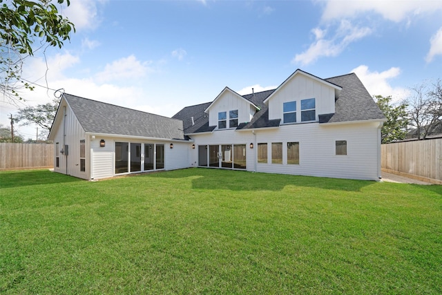 back of house featuring board and batten siding, a fenced backyard, a lawn, and roof with shingles