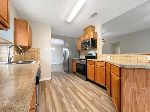 kitchen with light hardwood / wood-style flooring, stainless steel appliances, backsplash, and sink