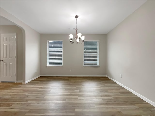 unfurnished room with plenty of natural light, a chandelier, and light hardwood / wood-style flooring