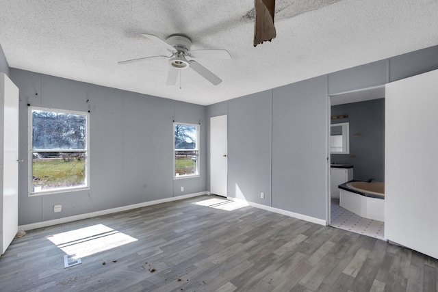 unfurnished bedroom featuring a textured ceiling, ceiling fan, connected bathroom, wood finished floors, and baseboards