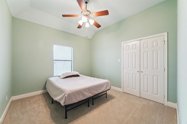 bedroom featuring light carpet, lofted ceiling, ceiling fan, and a closet