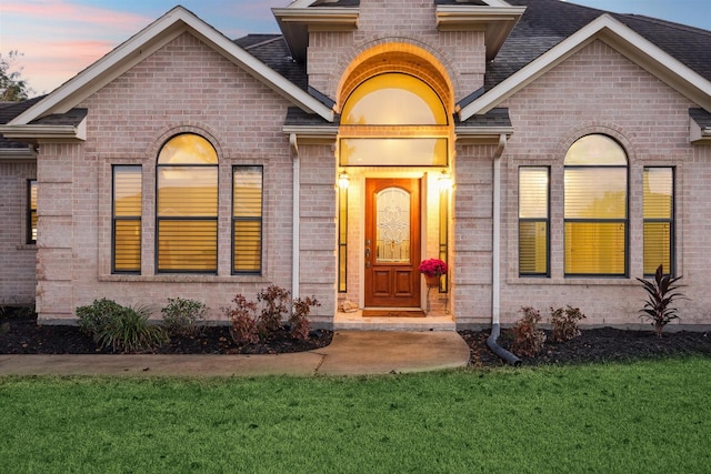 exterior entry at dusk featuring a yard