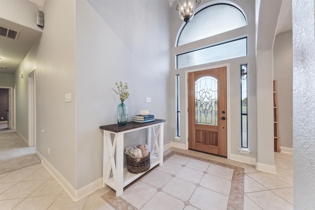 tiled foyer entrance with a towering ceiling and a notable chandelier