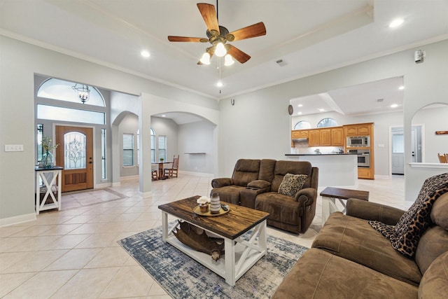 tiled living room featuring a tray ceiling, crown molding, and ceiling fan