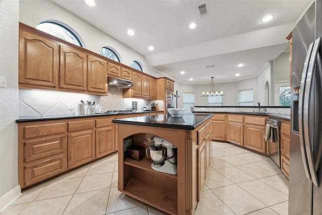 kitchen with appliances with stainless steel finishes, light tile patterned flooring, a center island, and decorative light fixtures