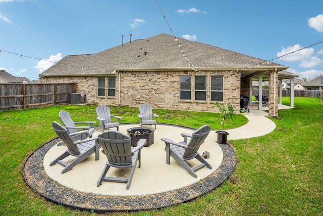 rear view of house featuring a fire pit, brick siding, fence, a lawn, and a patio area