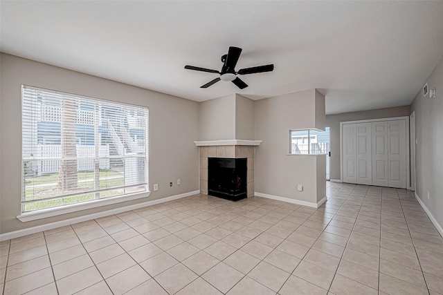 unfurnished living room with a tiled fireplace, ceiling fan, and light tile patterned floors