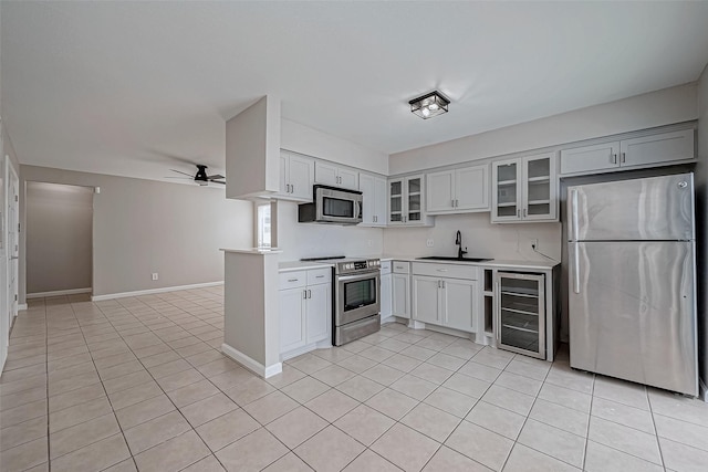 kitchen with appliances with stainless steel finishes, ceiling fan, light tile patterned floors, sink, and wine cooler