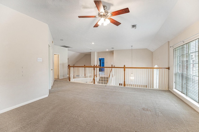 spare room with baseboards, visible vents, light colored carpet, ceiling fan, and vaulted ceiling