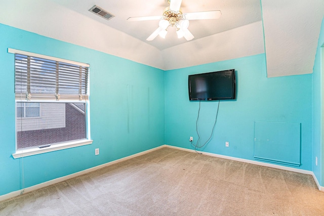 spare room featuring visible vents, a ceiling fan, carpet flooring, vaulted ceiling, and baseboards