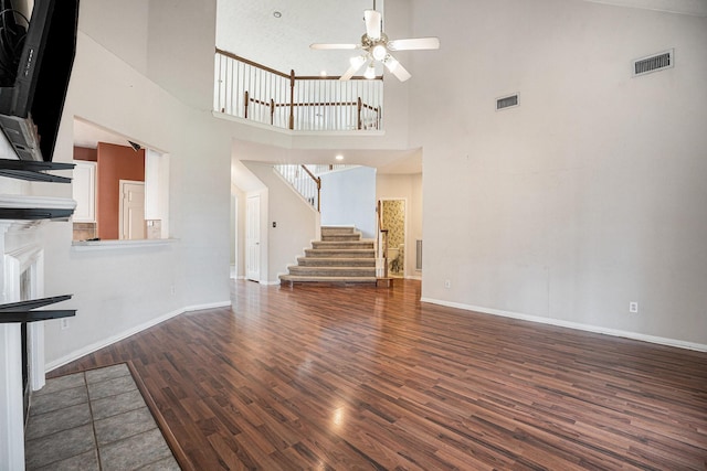 unfurnished living room featuring dark wood-style floors, stairway, visible vents, and baseboards