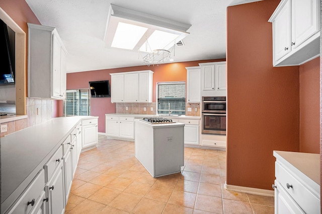 kitchen featuring stainless steel appliances, a skylight, white cabinets, and light countertops