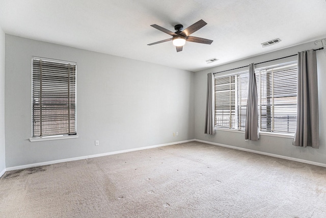 carpeted spare room with ceiling fan, visible vents, and baseboards