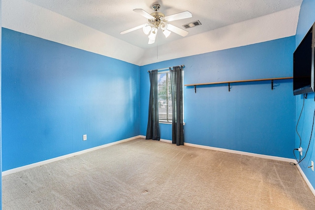 unfurnished room with ceiling fan, visible vents, baseboards, vaulted ceiling, and carpet