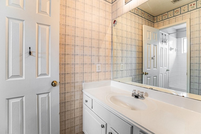 bathroom with visible vents, vanity, and wallpapered walls