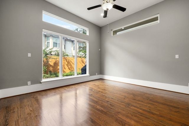 spare room with ceiling fan, plenty of natural light, and wood-type flooring