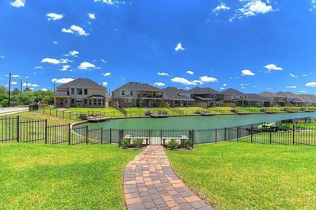 view of home's community with a water view and a lawn