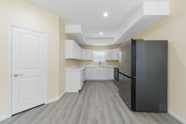 kitchen featuring freestanding refrigerator, a sink, electric range, and baseboards