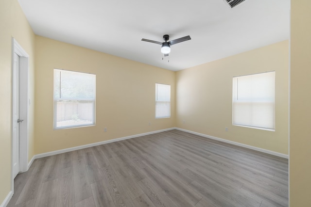 spare room with a ceiling fan, baseboards, visible vents, and light wood finished floors