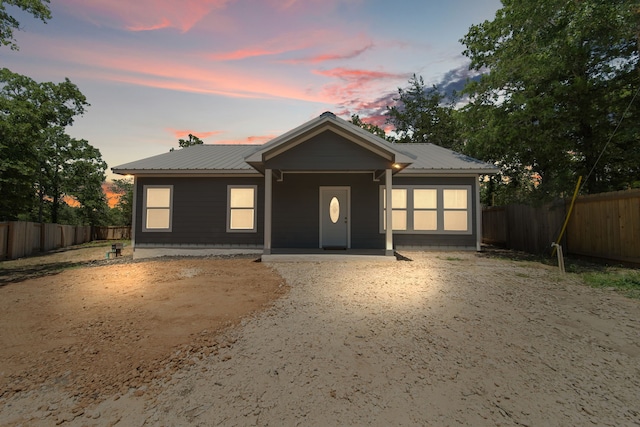 single story home featuring metal roof and fence