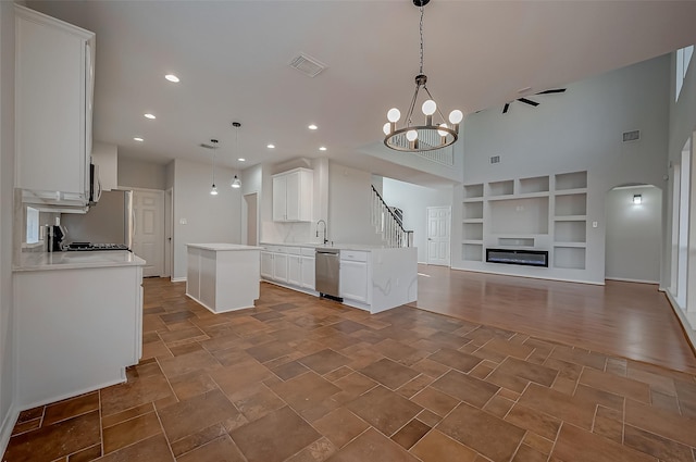 kitchen with white cabinetry, a kitchen island, an inviting chandelier, stainless steel dishwasher, and pendant lighting