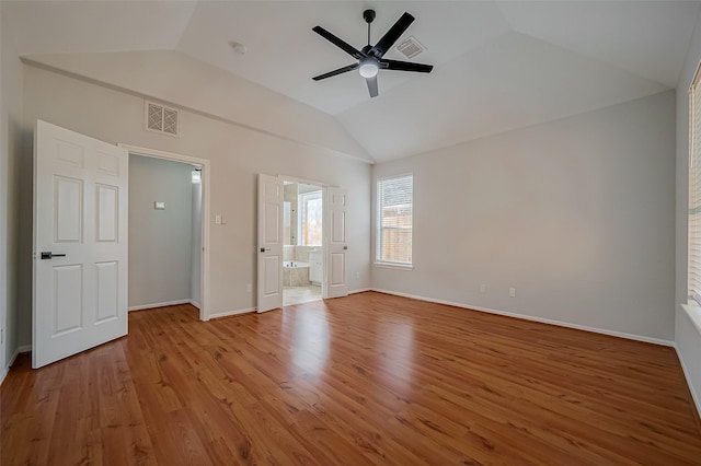 unfurnished bedroom featuring light wood-type flooring, lofted ceiling, ceiling fan, and ensuite bath