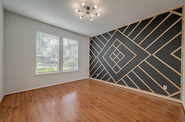 unfurnished room featuring a chandelier and hardwood / wood-style floors