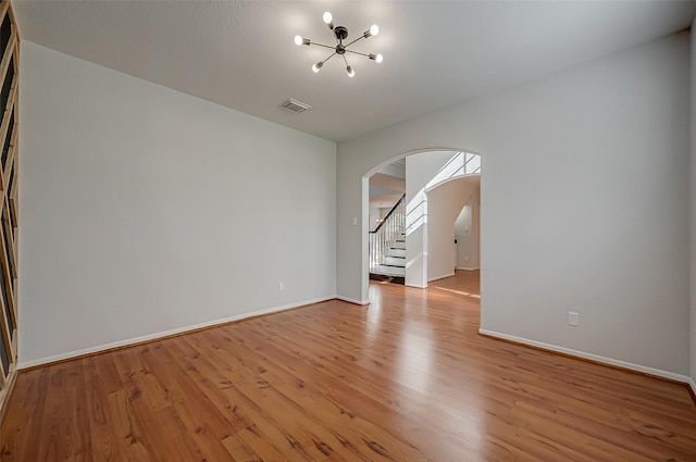 empty room with light hardwood / wood-style floors and a notable chandelier