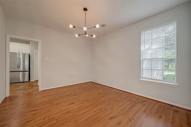 empty room featuring light hardwood / wood-style floors and a chandelier