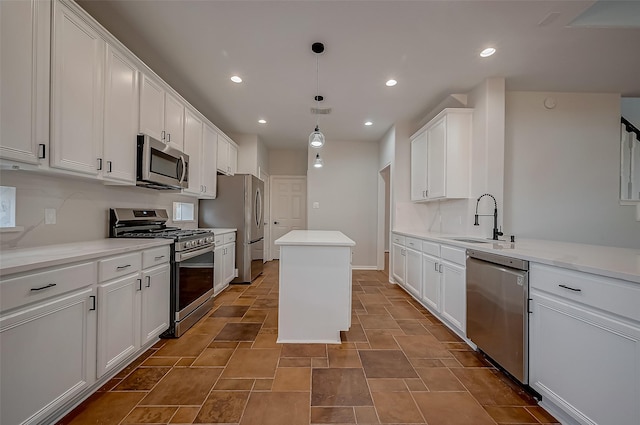 kitchen with appliances with stainless steel finishes, sink, white cabinetry, a kitchen island, and hanging light fixtures