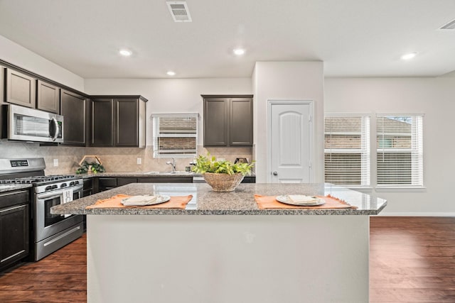 kitchen featuring light stone countertops, a kitchen island, stainless steel appliances, and a sink