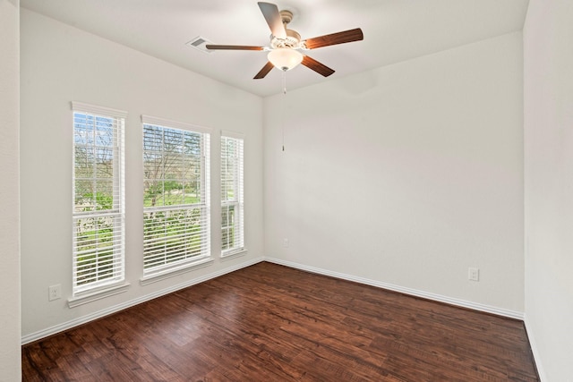 spare room with dark wood-style floors, baseboards, visible vents, and ceiling fan