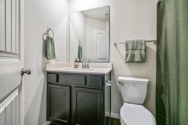 bathroom featuring visible vents, a textured wall, toilet, and vanity