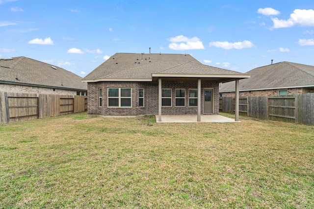 back of house featuring a yard, a patio, brick siding, and a fenced backyard