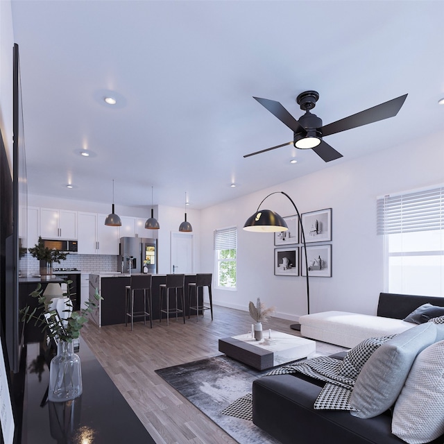 living area featuring wood finished floors, a ceiling fan, and baseboards