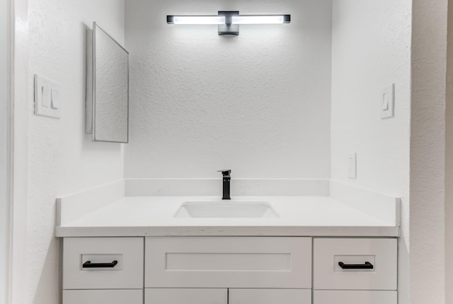 bathroom featuring a textured wall and vanity