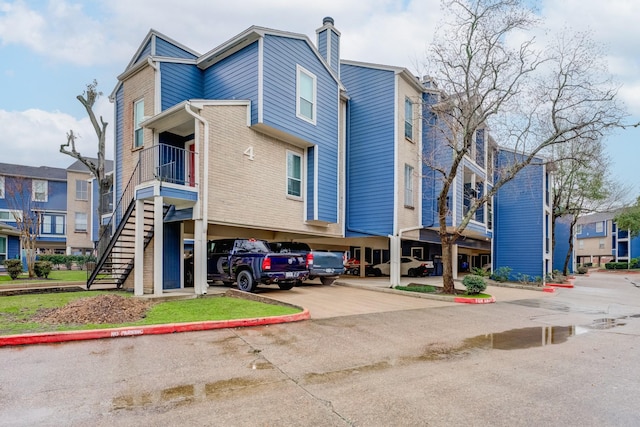 view of property with uncovered parking and stairway