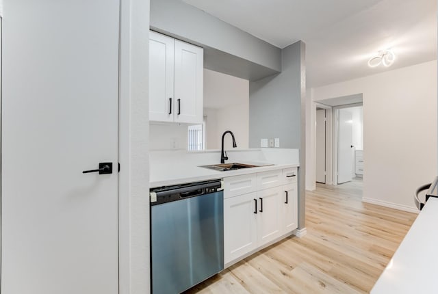 kitchen featuring light countertops, white cabinets, a sink, light wood-type flooring, and dishwasher