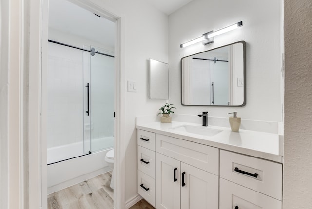 full bathroom with enclosed tub / shower combo, toilet, wood finished floors, and vanity