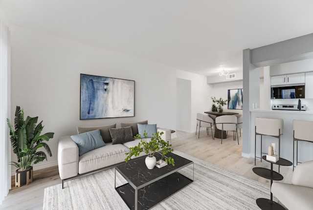 living room with baseboards, visible vents, and light wood finished floors