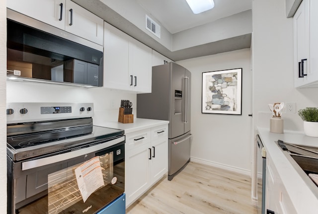 kitchen featuring light wood finished floors, stainless steel appliances, light countertops, visible vents, and white cabinets