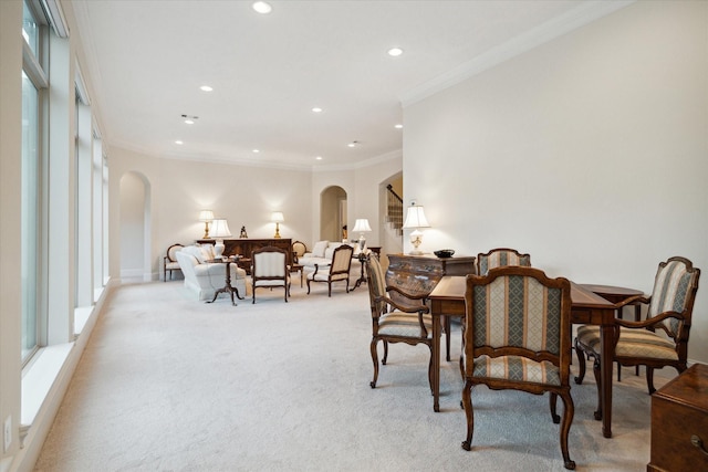 dining area with arched walkways, light colored carpet, crown molding, and recessed lighting