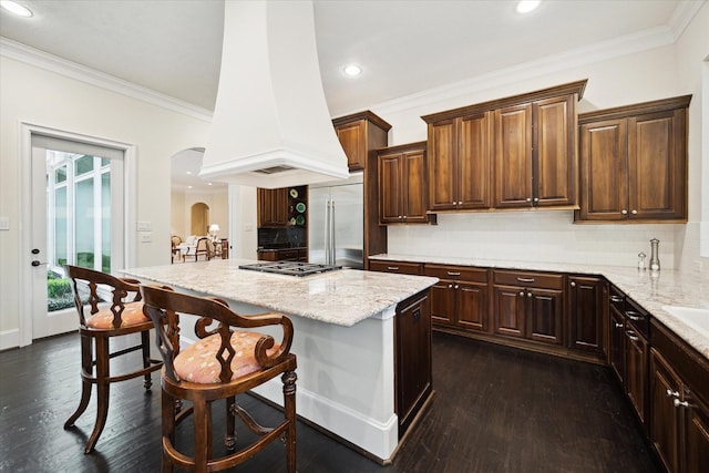 kitchen with island range hood, arched walkways, a kitchen island, a breakfast bar, and stainless steel appliances