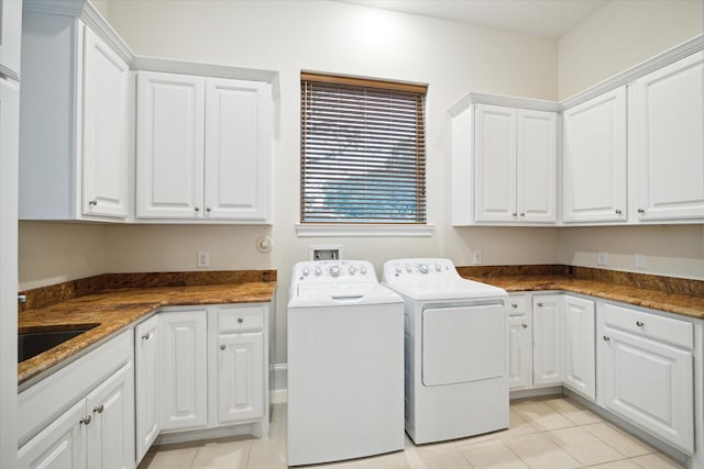 clothes washing area featuring light tile patterned floors, cabinet space, a sink, and separate washer and dryer